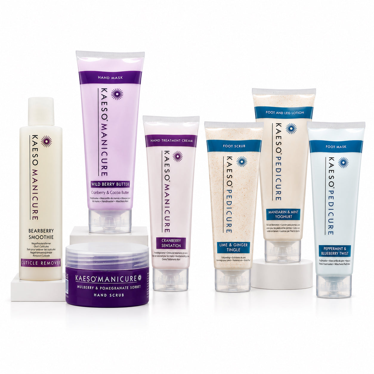 A collection of Kaeso Manicure & pedicure care products arranged on a white background, including cuticle remover, hand & nail treatment cream, hand scrub, hand  mask and foot scrub with mint extract. The products feature white, light purple, and light blue packaging with purple and blue text accents.
