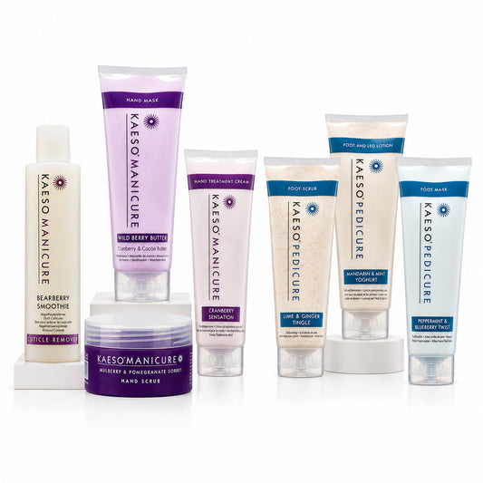 A collection of Kaeso Manicure & pedicure care products arranged on a white background, including cuticle remover, hand & nail treatment cream, hand scrub, hand  mask and foot scrub with mint extract. The products feature white, light purple, and light blue packaging with purple and blue text accents.